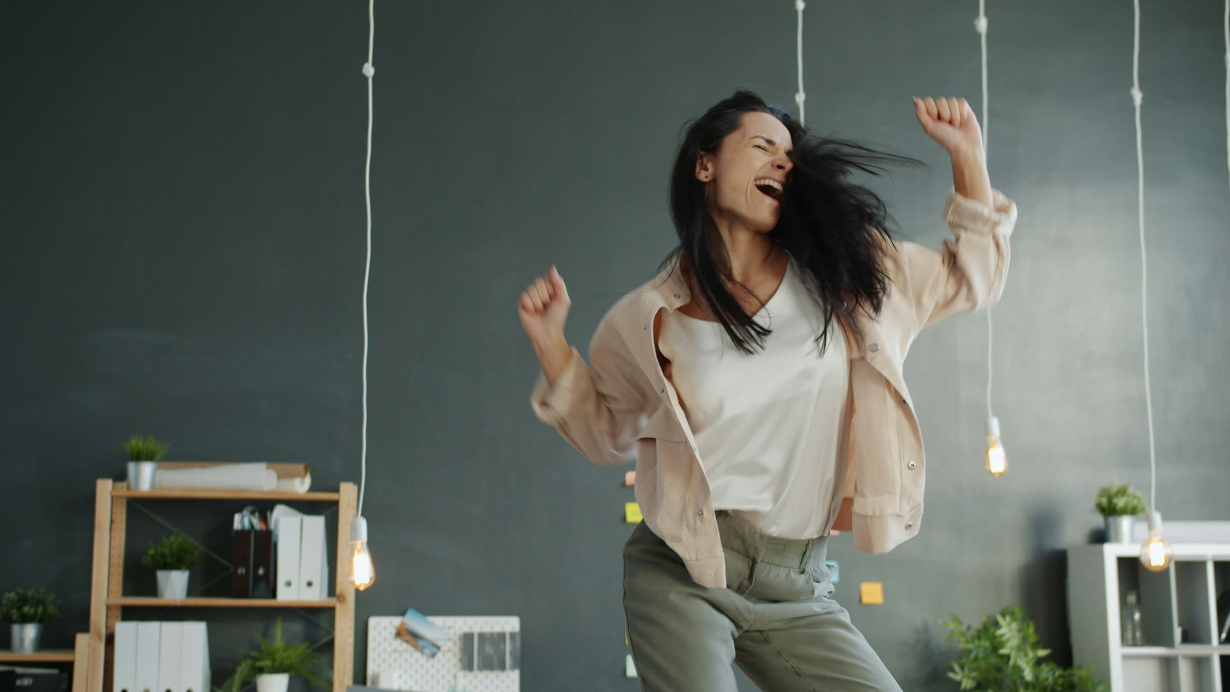 A woman joyfully dancing with arms raised.
