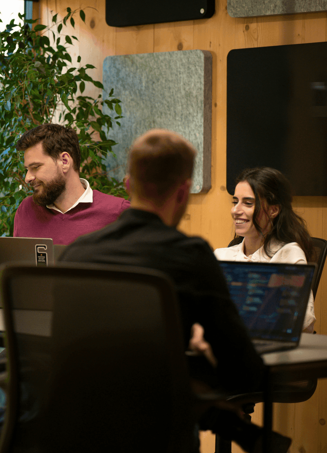 A group of people sitting around a table with laptops